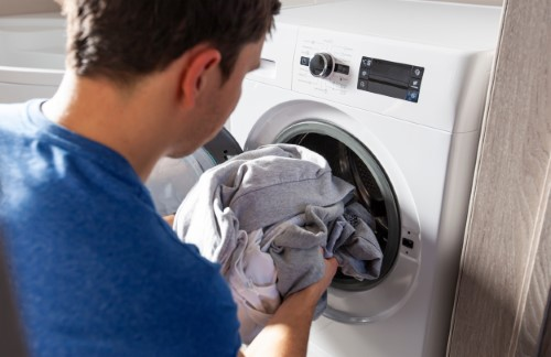 un homme insérant du linge dans sa machine à laver